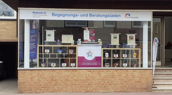 Schaufenster eines Ladens mit Banner "Begenungs- und Beratungsladen" sowie Logos "Diakonisches Werk Odenwald" und "GenerationenNetz Reichelsheim" sowie Plakaten und weiterer Deko